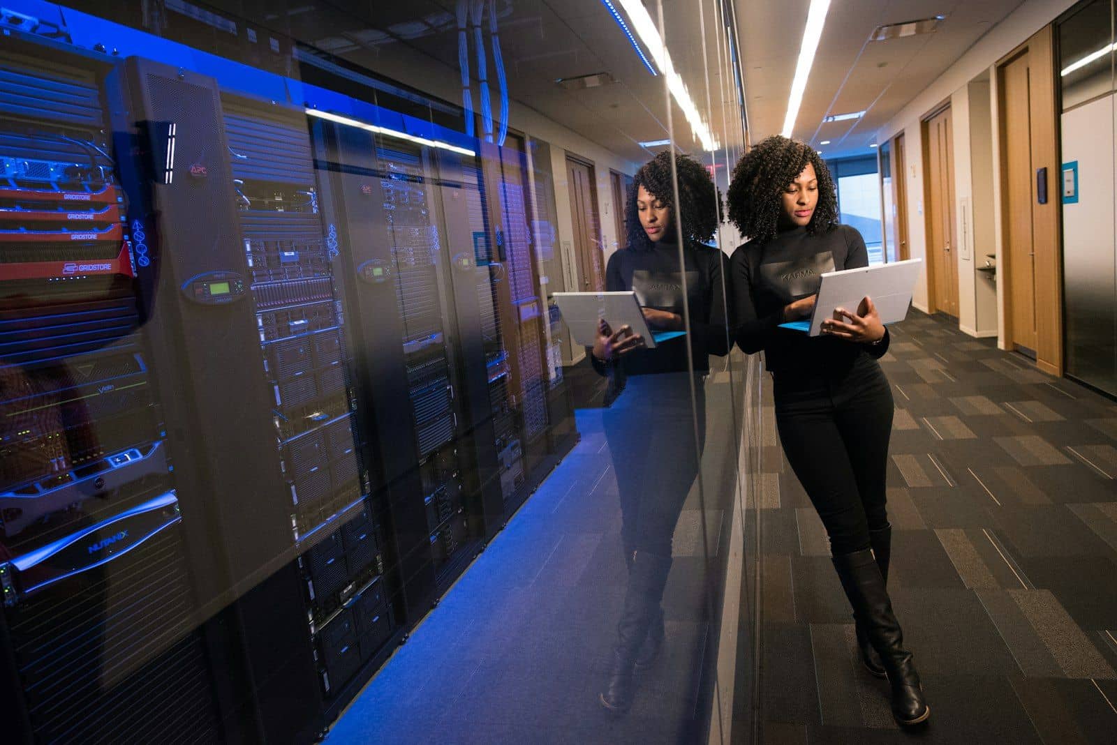 A person walking through a server room corridor holding a tablet